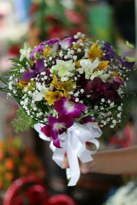 a close up of a person holding a bouquet of flowers, orchids, purple and yellow, white orchids, elegant!