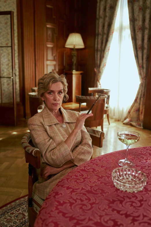 a woman sitting at a table with a glass of wine, grand budapest hotel, holding a cane, in spain, séance