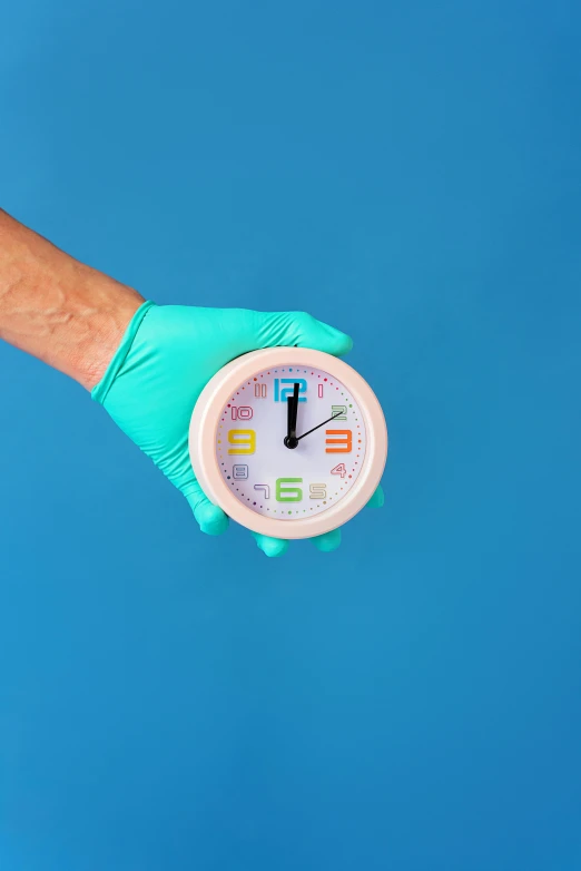 a gloved hand holding a clock against a blue background, inspired by Damien Hirst, trending on pexels, made of lab tissue, medical labels, professional product shot, brightly lit