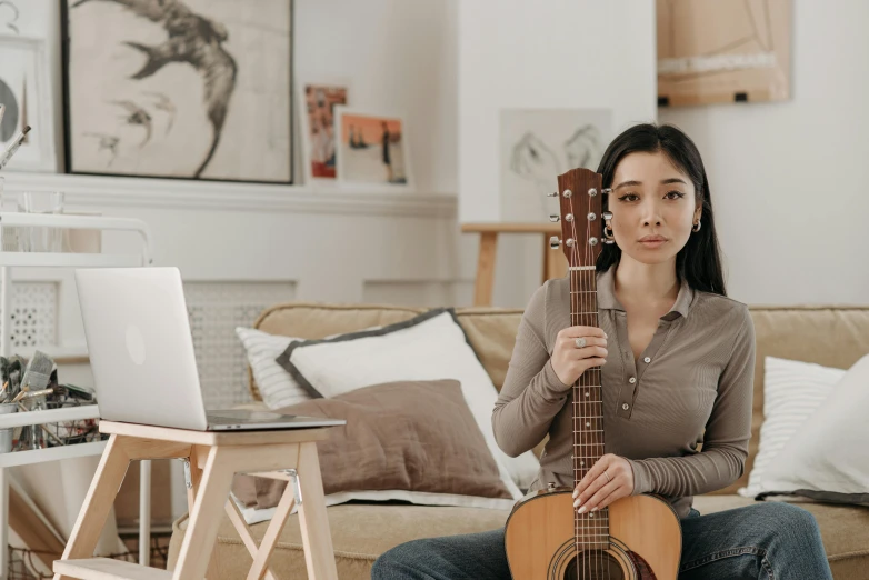 a woman sitting on a couch holding a guitar, inspired by Li Song, trending on pexels, concerned, sitting on a desk, student, profile image