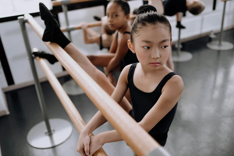 a group of young ballerinas in a dance studio, trending on pexels, of a youthful japanese girl, bench, black, looking serious