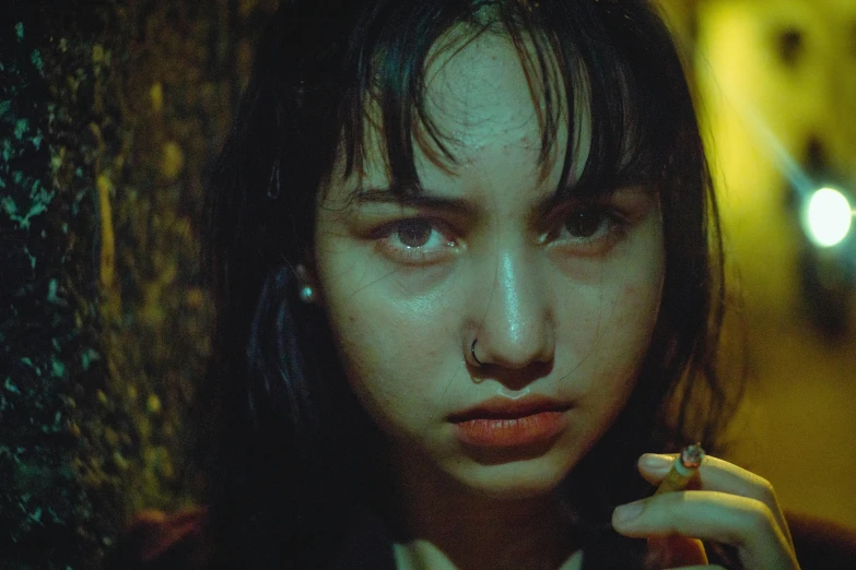 a close up of a person holding a cigarette, an album cover, inspired by Elsa Bleda, trending on pexels, realism, young asian girl, film still from horror movie, dilraba dilmurat, ugly look