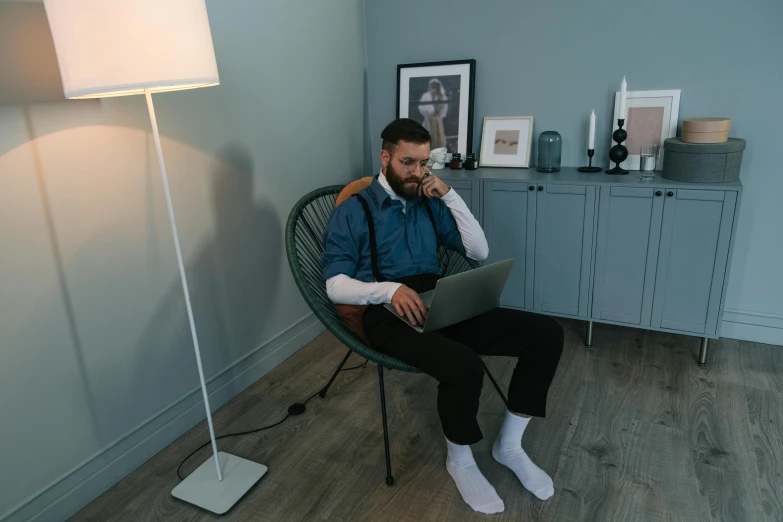 a man sitting in a chair using a laptop, by Adam Marczyński, pexels contest winner, hurufiyya, wearing only pants, lachlan bailey, sitting across the room, outfit photo