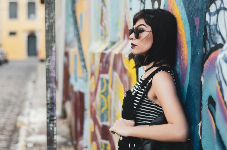 a woman leaning against a graffiti covered wall, trending on pexels, black stripes, charli xcx, tourist photo, spraypainted on a wall