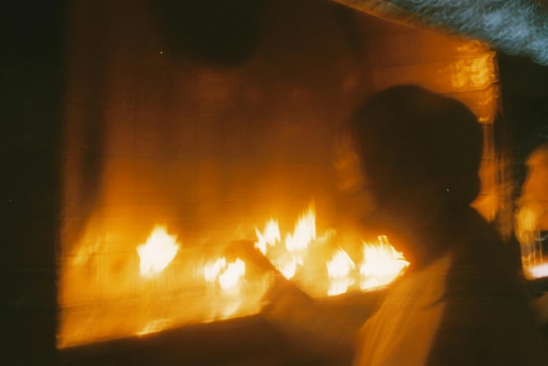 a man that is standing in front of a fire, profile image, close up photograph, wide film still, pov photo