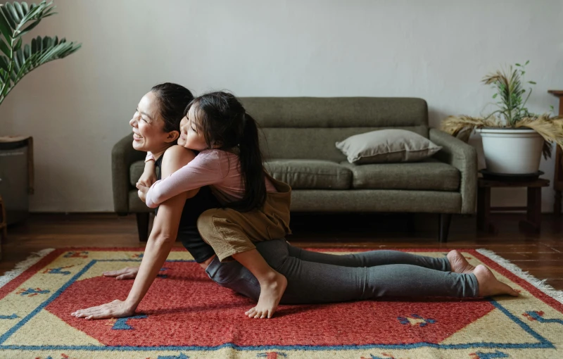 a woman and child sitting on a rug in a living room, pexels contest winner, marjaryasana and bitilasana, square, hugging each other, dynamic moving pose