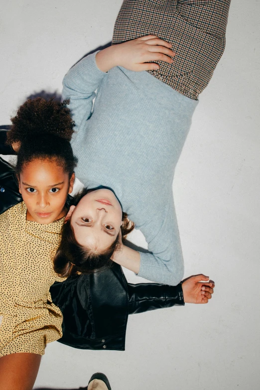 a couple of people laying on top of each other, by Nina Hamnett, trending on unsplash, kids, at a fashion shoot, show, looking up at camera