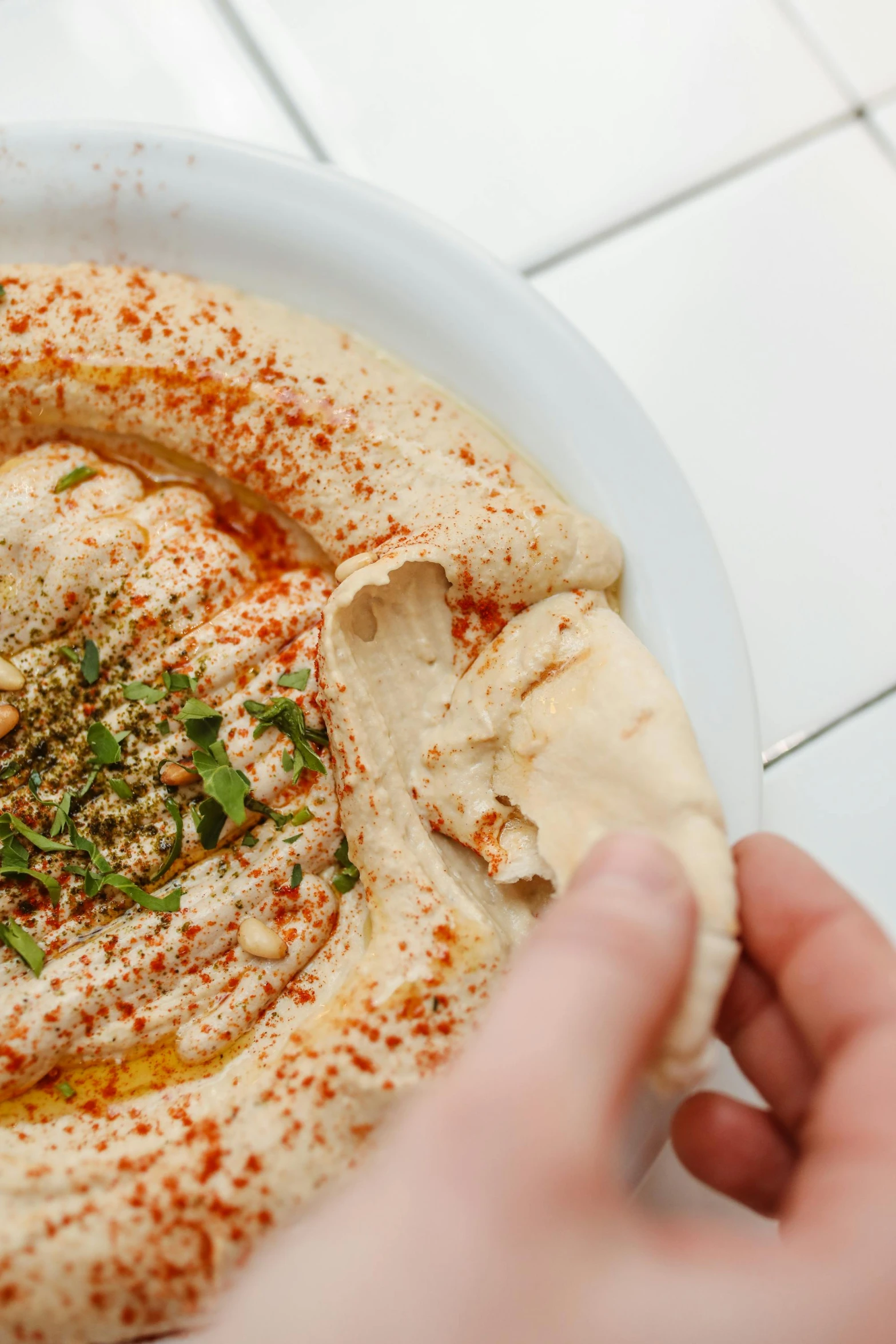 a close up of a plate of food on a table, dau-al-set, humus, hand holding a knife, swirling around, lush