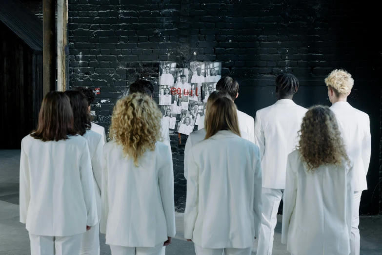 a group of people standing next to each other, inspired by Vanessa Beecroft, trending on pexels, serial art, her hair is white, wearing a labcoat, hidden message, performing a music video