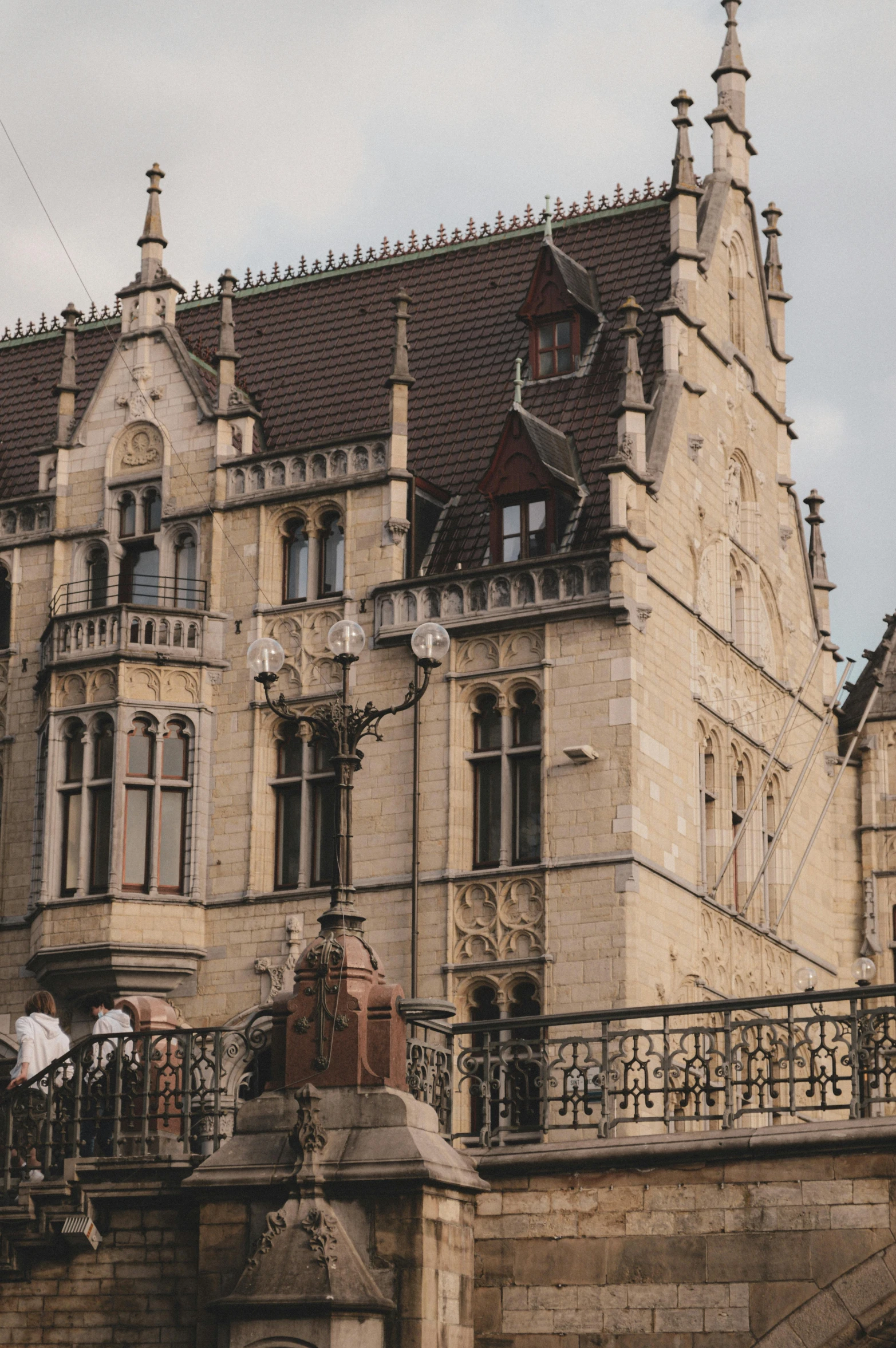 a couple of people that are standing in front of a building, inspired by Mihály Munkácsy, pexels contest winner, renaissance, gothic mansion, built on a steep hill, gargoyles, lower saxony