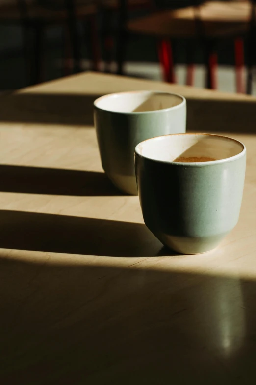 two cups of coffee sit on a table, inspired by Inshō Dōmoto, smooth shadows, carefully crafted, sundown, curated collections