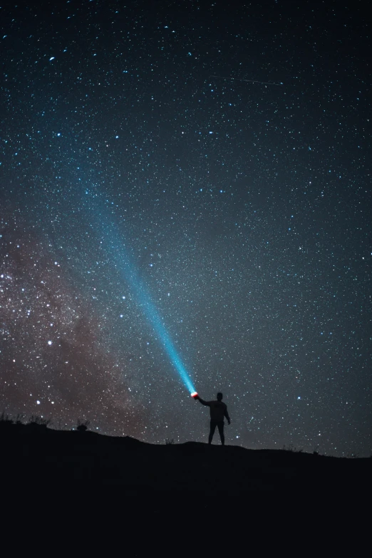 a person standing on top of a hill under a sky full of stars, pexels contest winner, light and space, holding a light saber, standing in the solar system, blue and red lights, comet