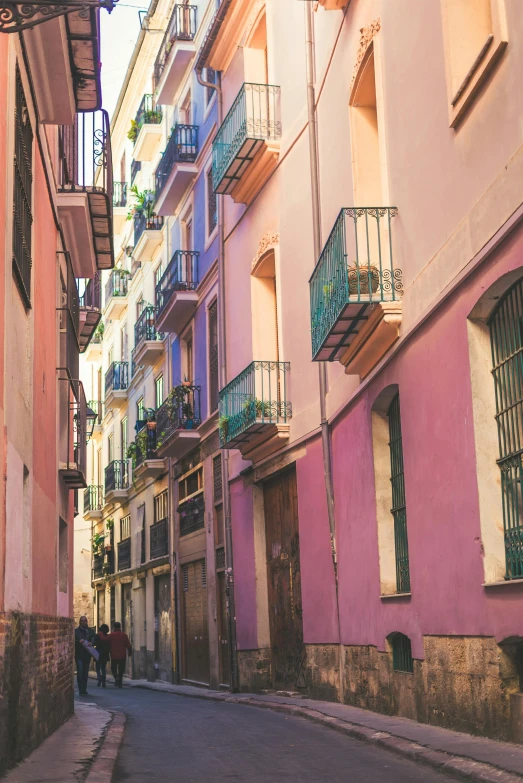 a couple of people walking down a narrow street, inspired by Ricardo Bofill, pexels contest winner, pastel bright colors, palermo city street, balconies, ( colorful )