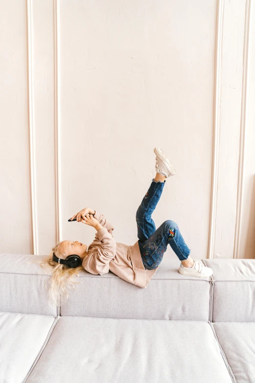 a woman laying on top of a white couch, trending on pexels, girl wearing headphones, fullbody photo, happy kid, wearing denim