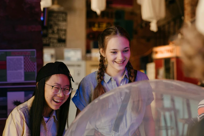 a couple of women standing next to each other, interactive art, inside a globe, tactile buttons and lights, teenager hangout spot, inside an old magical sweet shop