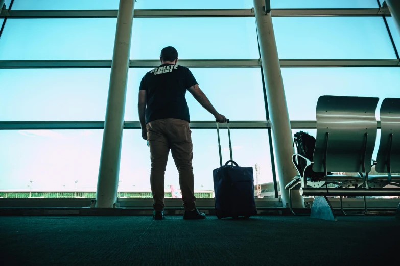 a man standing next to a luggage bag in an airport, by Julia Pishtar, pexels contest winner, happening, looking out a window, thumbnail, about to enter doorframe, lachlan bailey