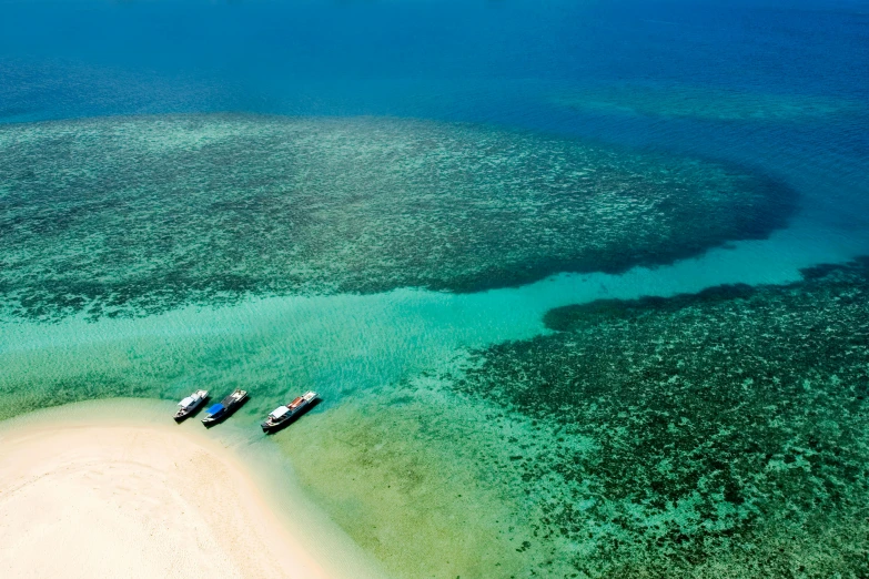 a couple of boats sitting on top of a sandy beach, coral sea bottom, crystal clear neon water, bird's eye, white beaches