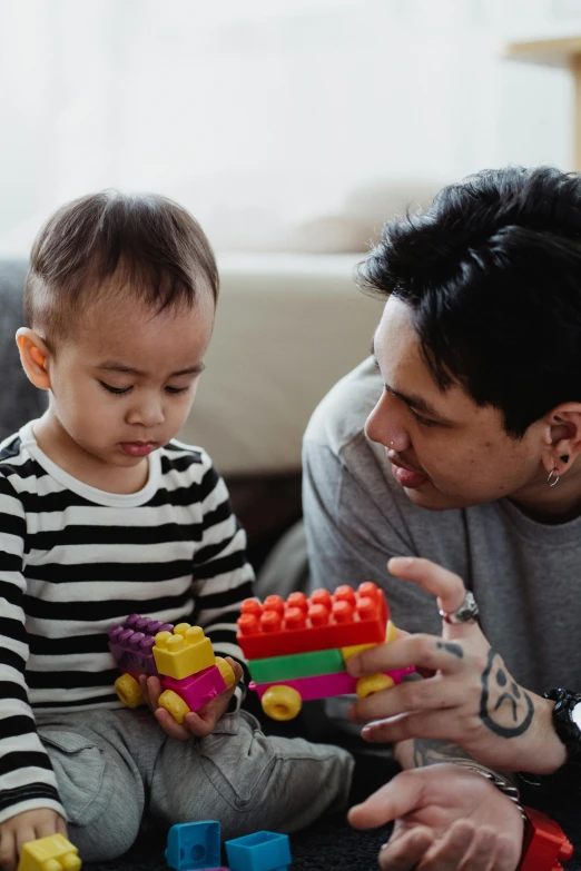 a man playing with a child on the floor, a cartoon, pexels contest winner, building blocks, looking serious, asian male, square