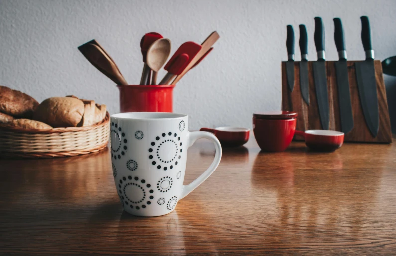 a coffee cup sitting on top of a wooden table, a still life, pexels contest winner, cutlery, red white and black color scheme, cute kitchen, gif