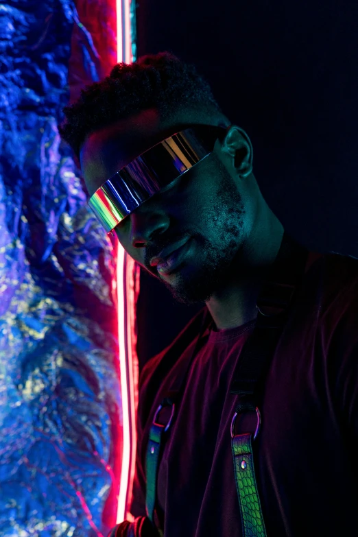 a man standing in front of a wall with neon lights, trending on pexels, afrofuturism, futuristic glasses lenses, ( ( dark skin ) ), iridescent visor, red reflective lens