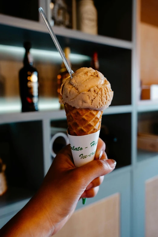 a person holding an ice cream cone in their hand, vine twist, daily specials, brown, chilean