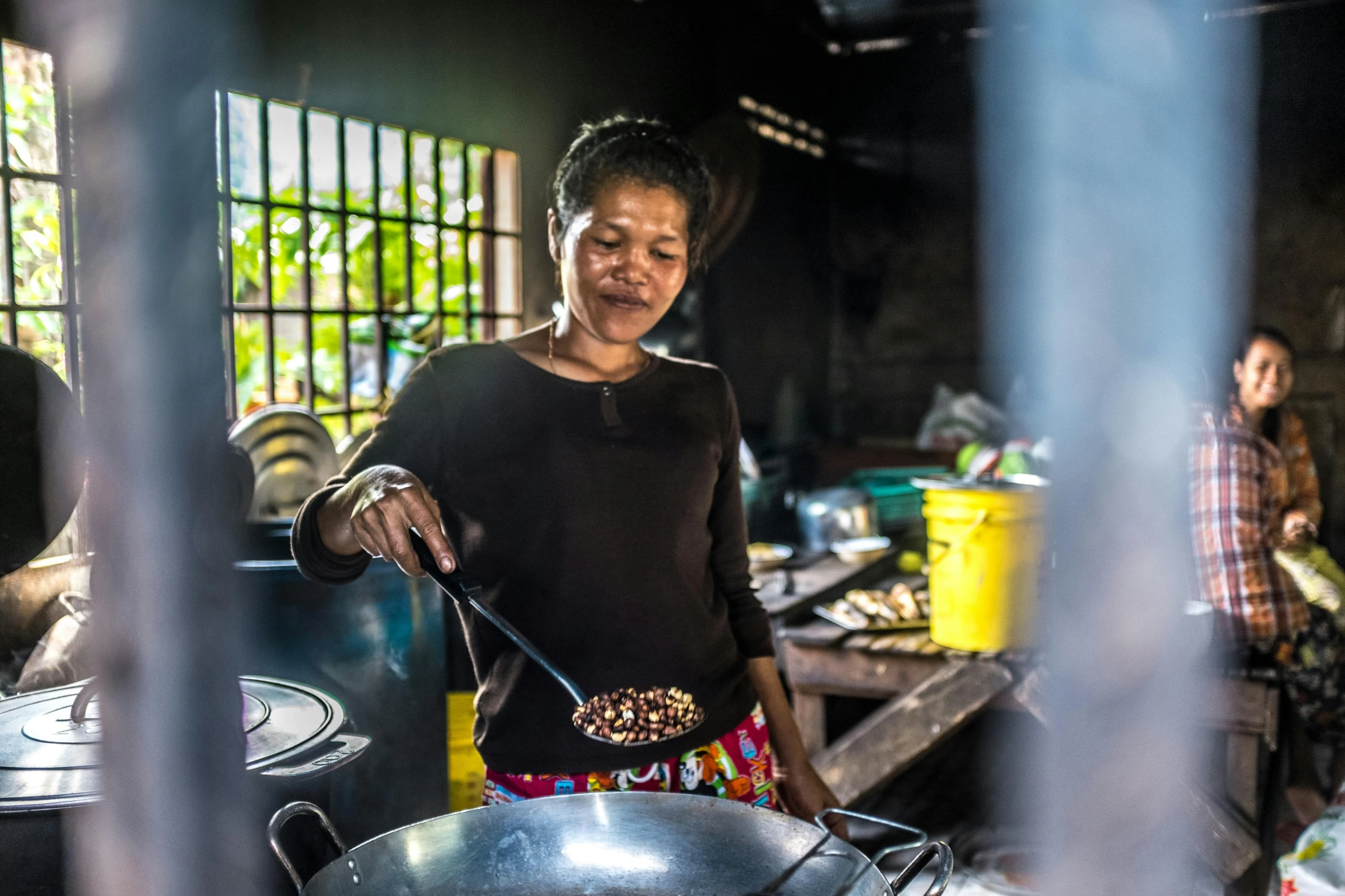 a woman standing in front of a wok filled with food, nuttavut baiphowongse, portrait image