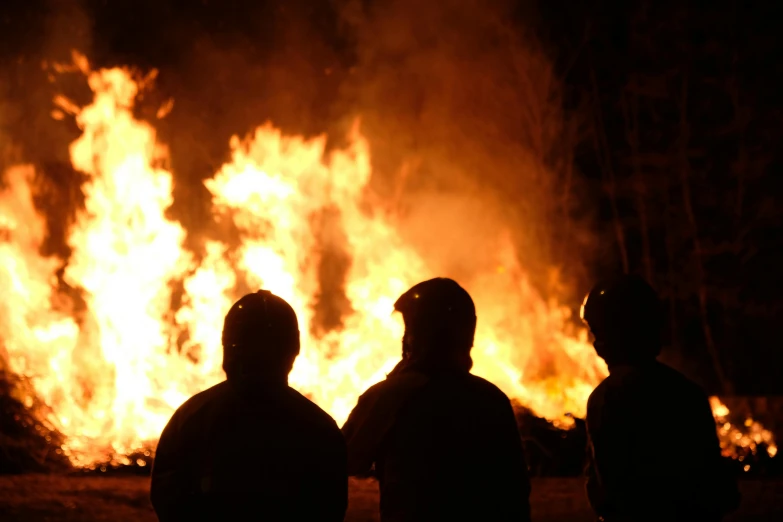 a group of people standing in front of a fire, at night, profile image, during the night