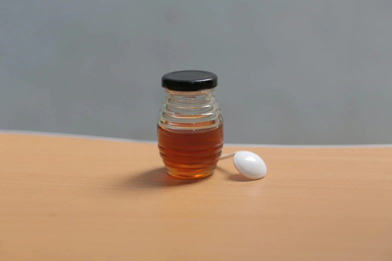 a bottle of honey sitting on top of a wooden table, a photorealistic painting, by Jan Rustem, photorealism, an egg, miniatures, photorealistic-n 9, white