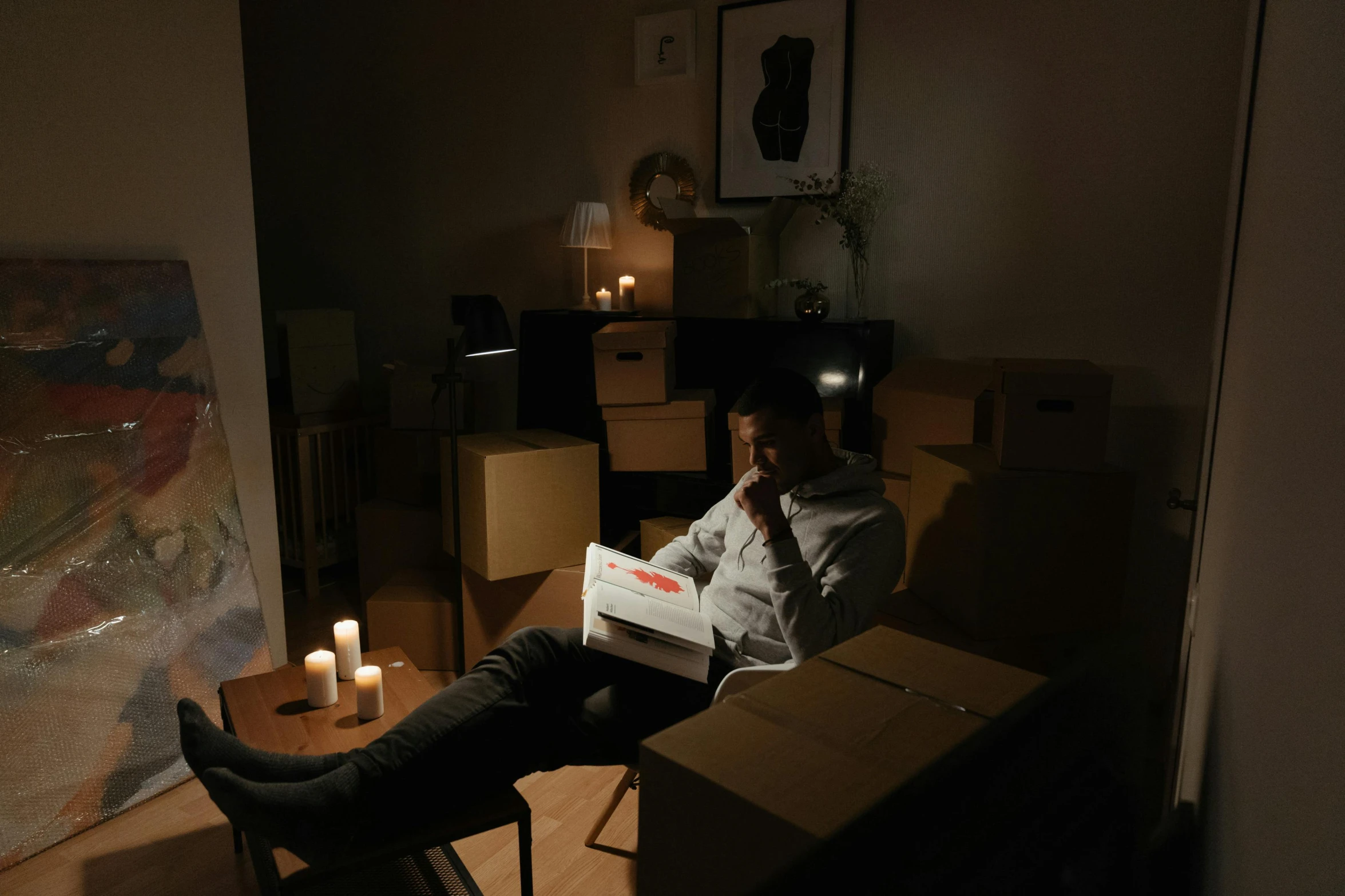 a man sitting in a chair reading a book, an album cover, pexels contest winner, room full of candles, cardboard, sitting at a computer, long distance photo