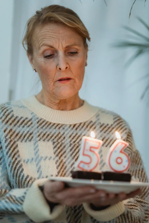 a woman holding a birthday cake with lit candles, pexels contest winner, hyperrealism, he is about 50 years old, 6 6 6, they are very serious, minna sundberg