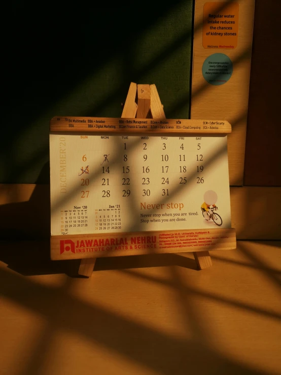 a calendar sitting on top of a wooden easer, a picture, by Kinichiro Ishikawa, promotional, jakarta, small, (1 as december