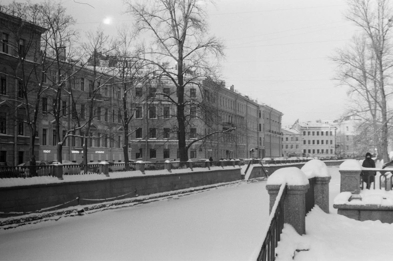 a black and white photo of people walking in the snow, a black and white photo, bauhaus, building along a river, saint petersburg, 1 7 8 0, view from the street