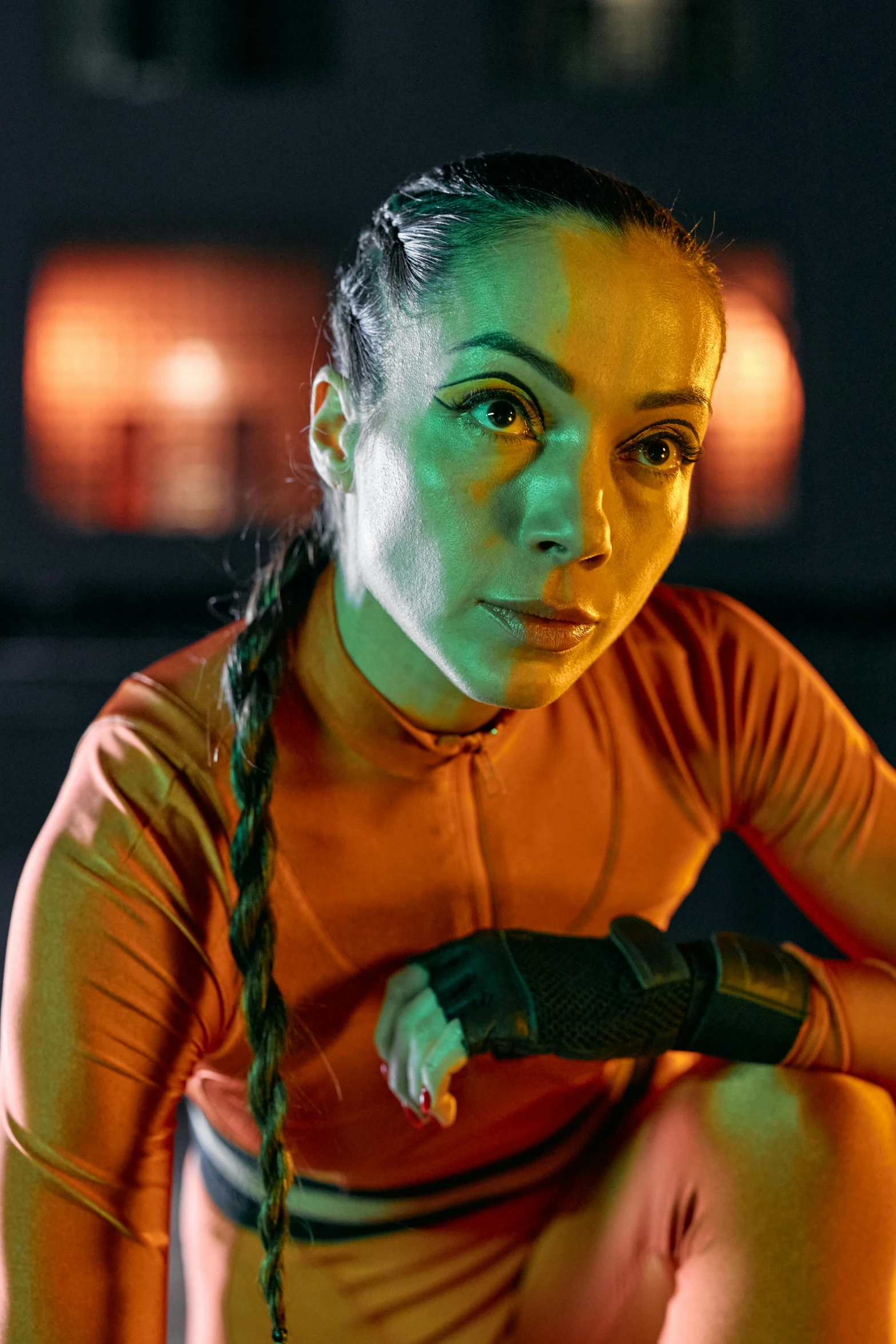 a woman squatting on the ground holding a tennis racquet, a portrait, pexels contest winner, antipodeans, orange and cyan lighting, wearing space techwear, in a gym, oona chaplin