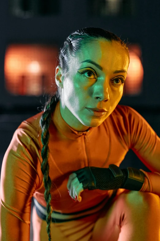 a woman squatting on the ground holding a tennis racquet, a portrait, pexels contest winner, antipodeans, orange and cyan lighting, wearing space techwear, in a gym, oona chaplin