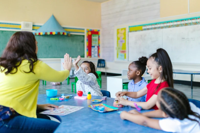 a woman giving a high five to a group of children, pexels contest winner, american barbizon school, sitting in the classroom, rule of thirds, colorful scene, thumbnail