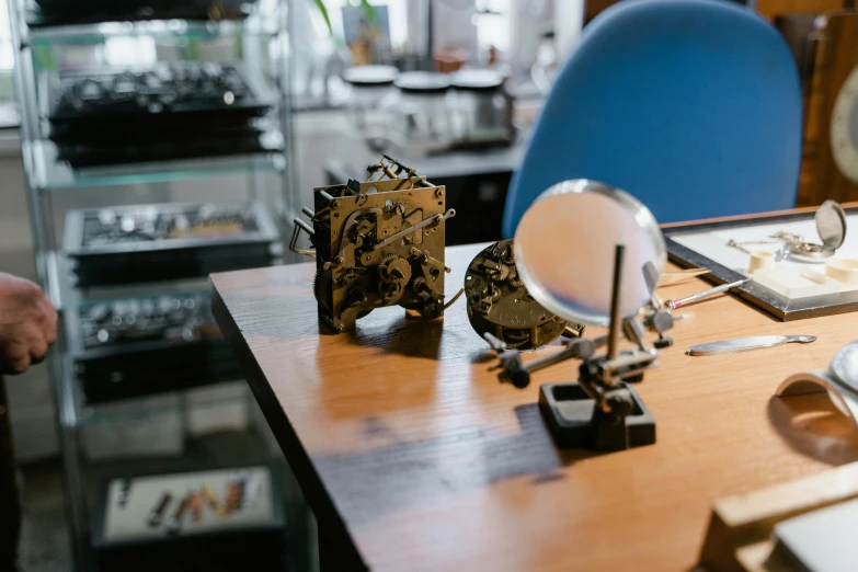 a wooden table topped with a clock next to a blue chair, an etching, unsplash, kinetic art, robot repair workshop, thumbnail, profile pic, intricate electronics