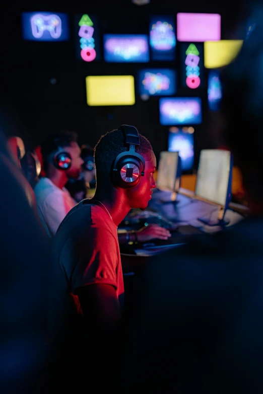 a group of people playing a video game, blue and red lights, headphones on, from the distance, headshot