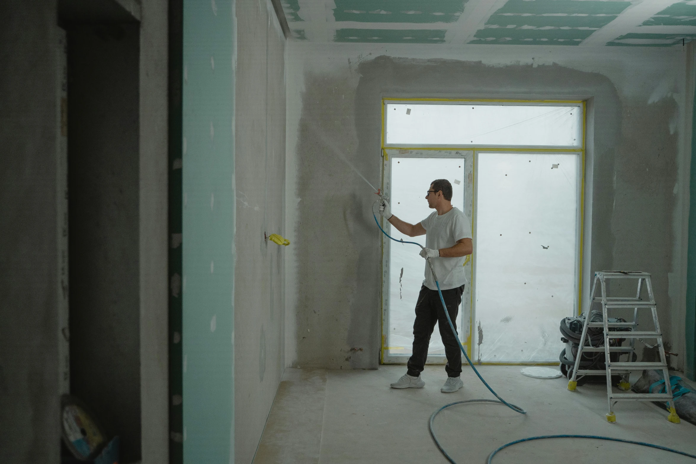 a man that is standing in a room with a hose, walls are made of dry wall, profile image, maintenance, worksafe. cinematic