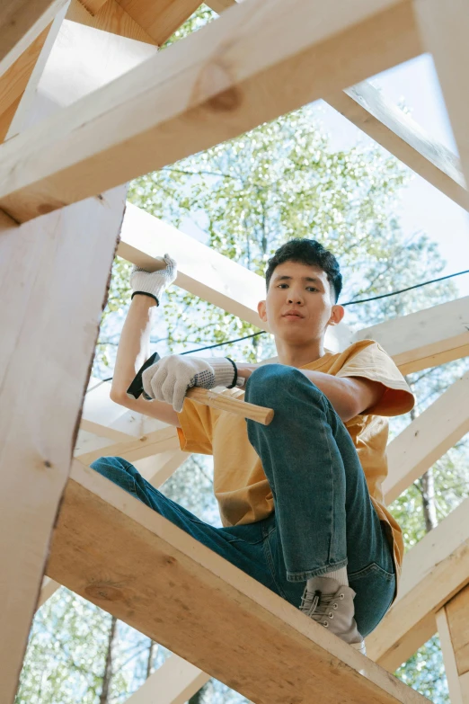 a man sitting on top of a wooden structure, a portrait, inspired by John Luke, pexels contest winner, visual art, portrait of a japanese teen, construction, lgbtq, inside a shed
