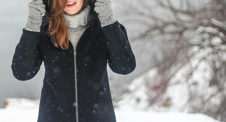 a woman in a black coat standing in the snow, pexels contest winner, grey hoodie, skincare, background image, girl with brown hair