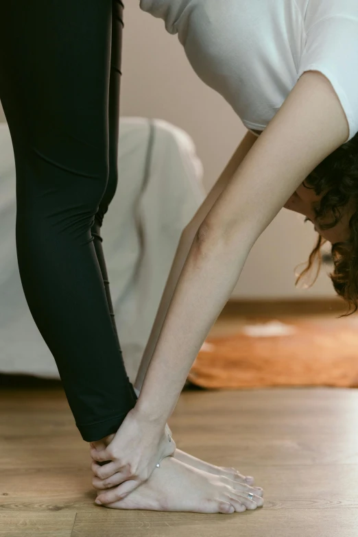 a woman doing a handstand on a hard wood floor, pexels contest winner, renaissance, leggings, woman holding another woman, running shoes, low quality photo