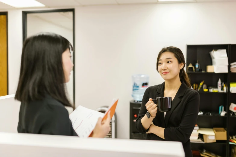 a woman talking to another woman in an office, by Simon Gaon, next to a cup, darren quach, lachlan bailey, high-quality photo