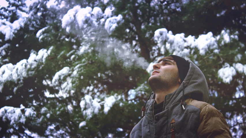 a man standing in front of snow covered trees, a picture, inspired by Elsa Bleda, unsplash, conceptual art, harry potter smoking weed, profile image, low quality footage, low angle shot