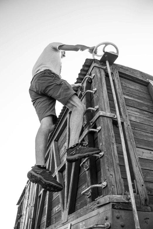 a man climbing up the side of a train car, a black and white photo, athletic crossfit build, carrying survival gear, on a pirate ship, worksafe. instagram photo