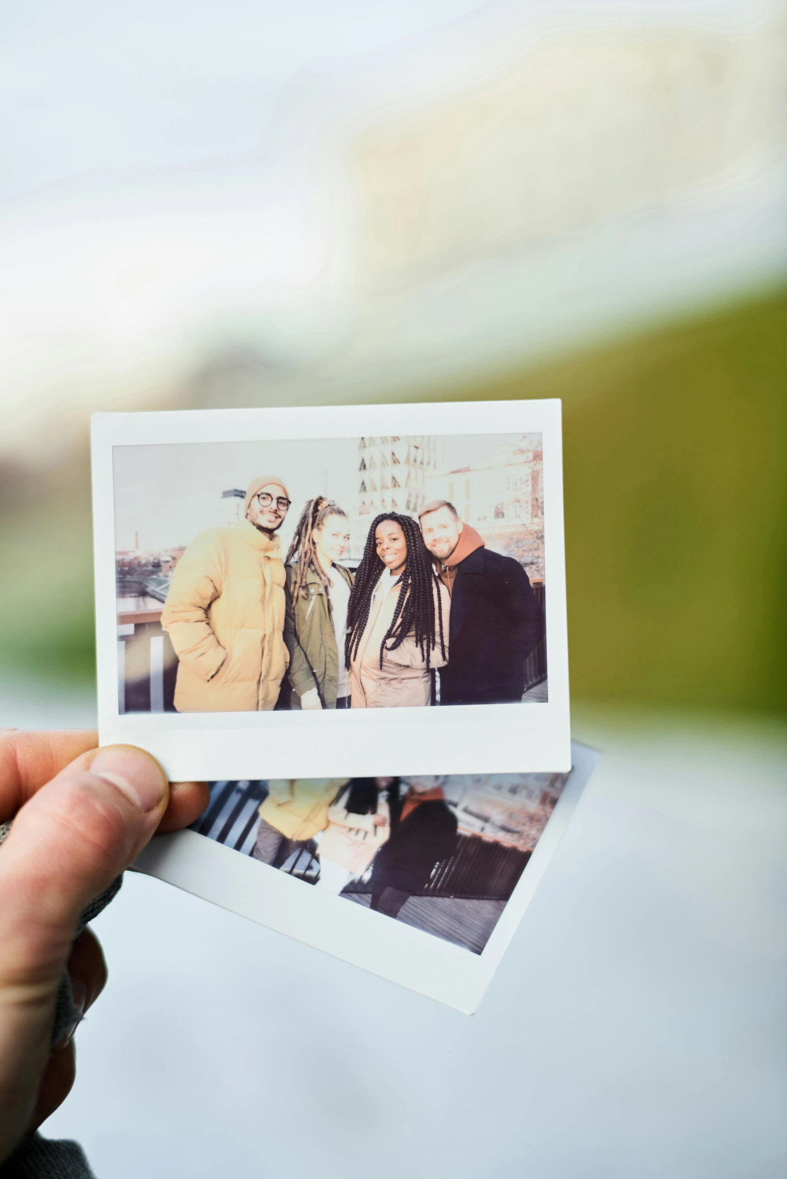 a person holding two polaroids in their hands, a polaroid photo, by Lucia Peka, pexels contest winner, two models in the frame, a group of people, tourist, slightly overexposed