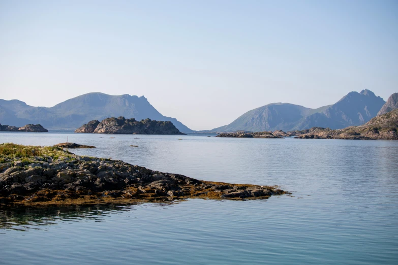 a body of water with mountains in the background, by Roar Kjernstad, pexels contest winner, hurufiyya, two medium sized islands, mediterranean, frederik heyman, sparsely populated