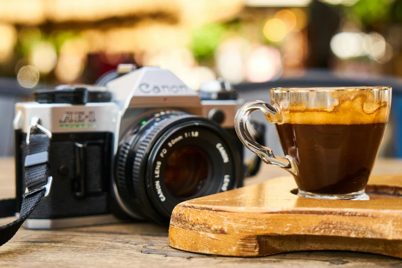 a camera and a cup of coffee on a table, pexels contest winner, cold brew coffee ), canon a1, arabica style, medium format