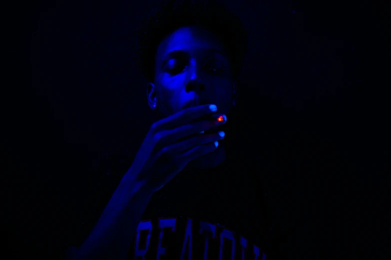 a woman smoking a cigarette in the dark, by Maxwell Bates, pexels contest winner, black teenage boy, red and blue black light, ashteroth, he has a glow coming from him