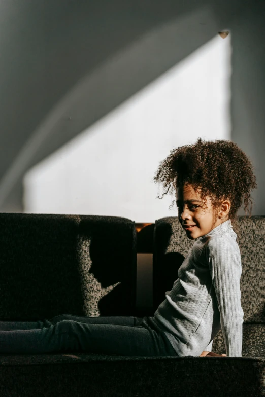 a little girl sitting on top of a couch, pexels contest winner, light and space, black teenage boy, with textured hair and skin, sunbeam, high-resolution