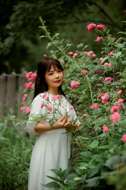 a woman in a white dress holding a bunch of flowers, an album cover, inspired by Kim Du-ryang, pexels contest winner, rose garden, lovingly looking at camera, mai anh tran, medium format. soft light